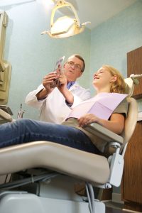 Low angle of a dentist pointing to a teen girl's dental x-rays during an examination Functional Dentistry